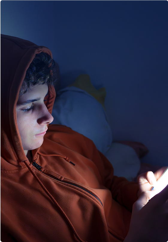 Teenager using a smartphone lying in bed late at night
