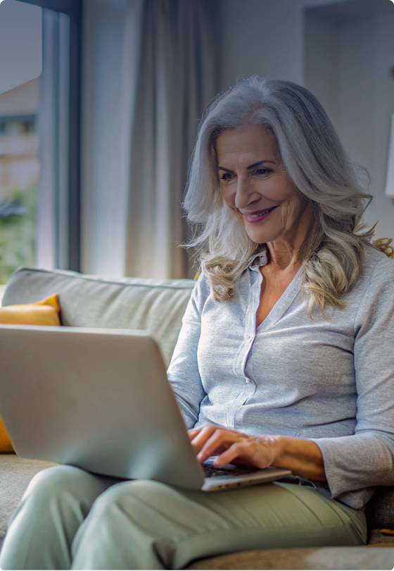 A woman is sitting on a couch and using a laptop