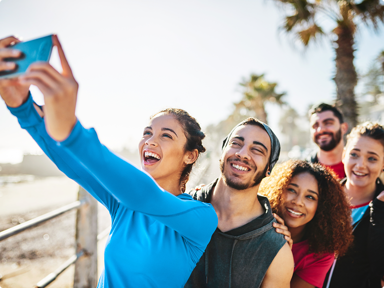 Group of young people taking a selfie along a beach boardwalk