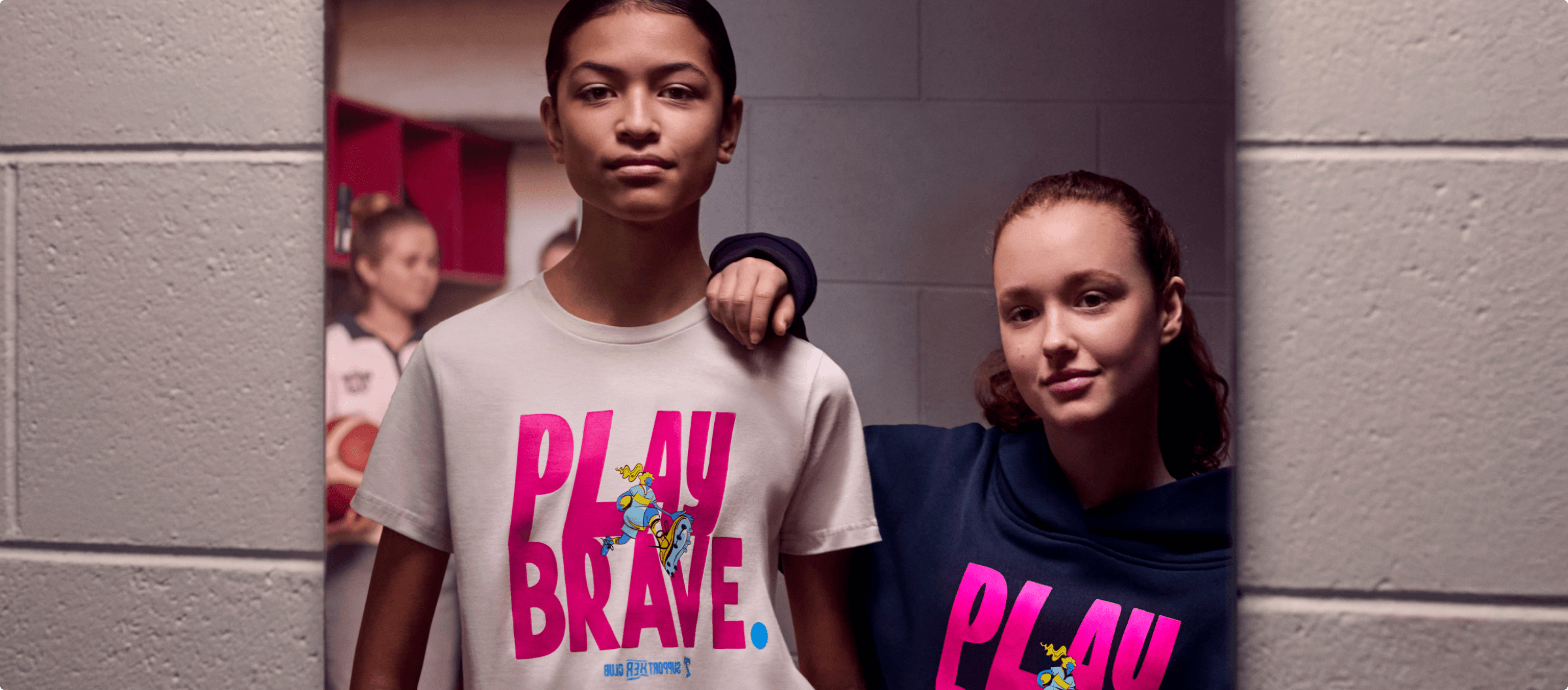 Photo of two girls wearing the SupportHER merch and looking in a mirror