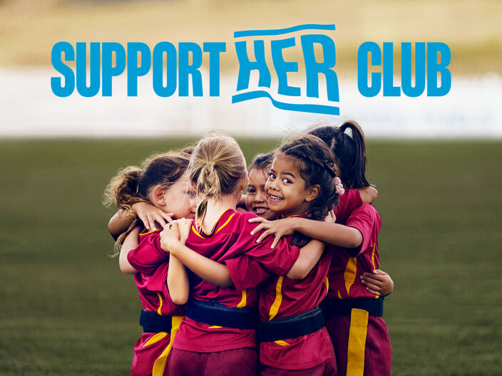 picture of young girls on rugby field with their arms around each other